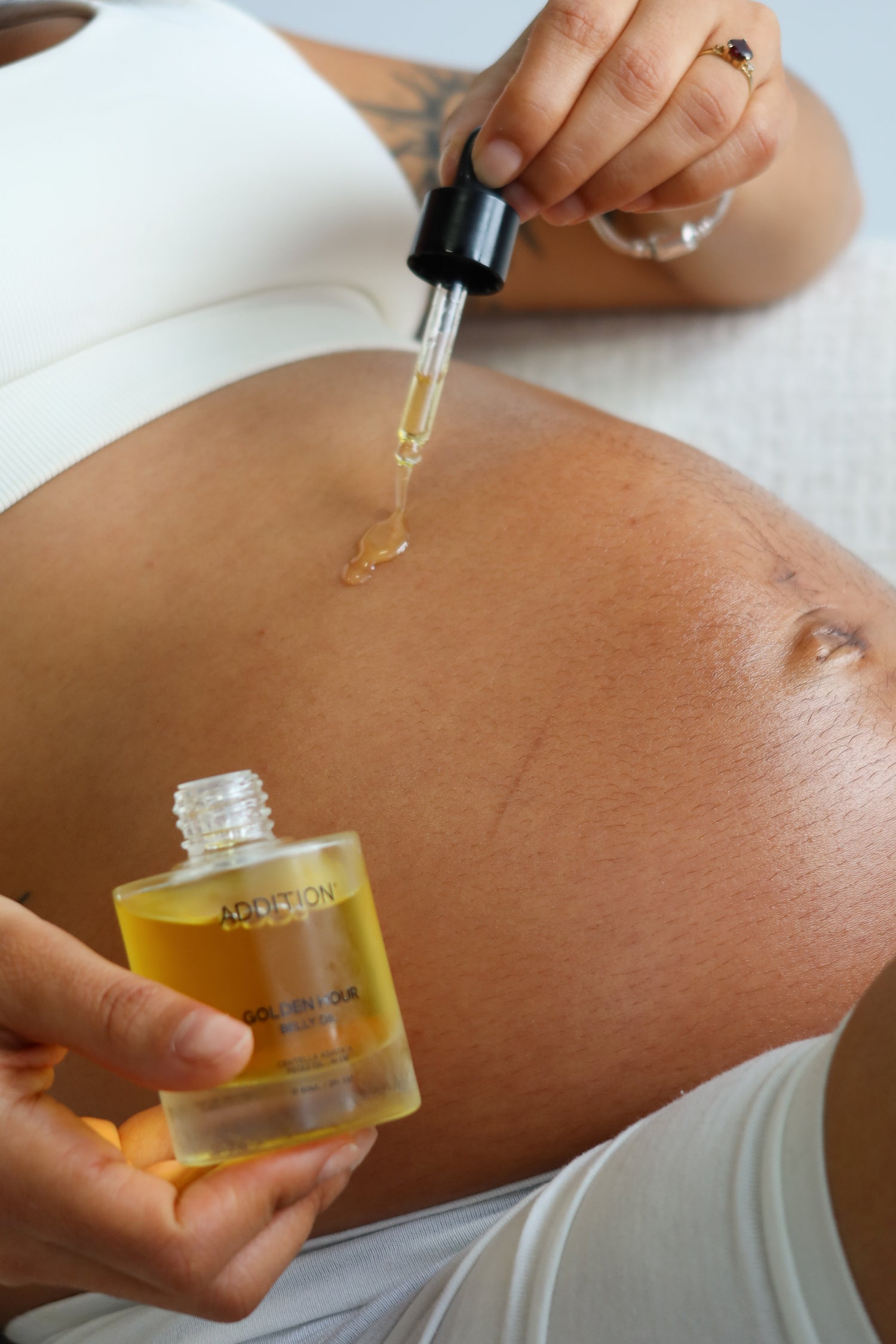 Golden Hour Belly Oil being applied to a pregnant belly with a glass dropper