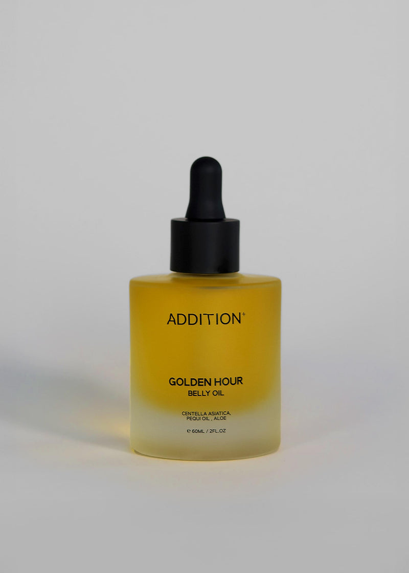 A bottle of ADDITION Golden Hour Belly Oil with a black dropper cap and a yellow-to-clear gradient bottle, set against a plain light gray background.